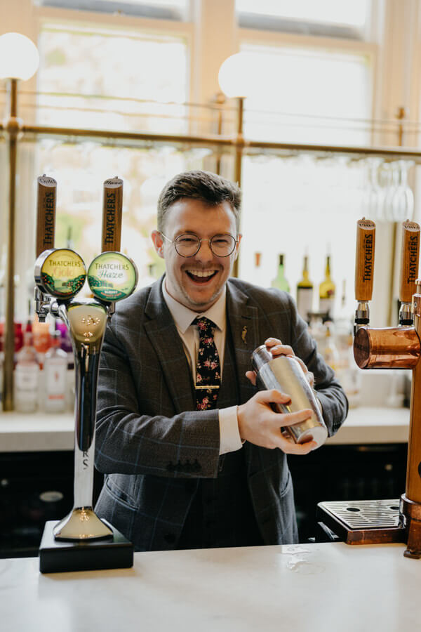a man in a suit holding a cocktail shaker