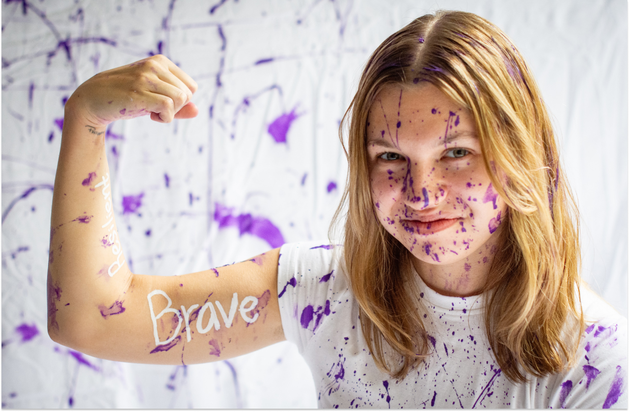 Sophia @strivewithsoph flexing her arm with the word brave painted