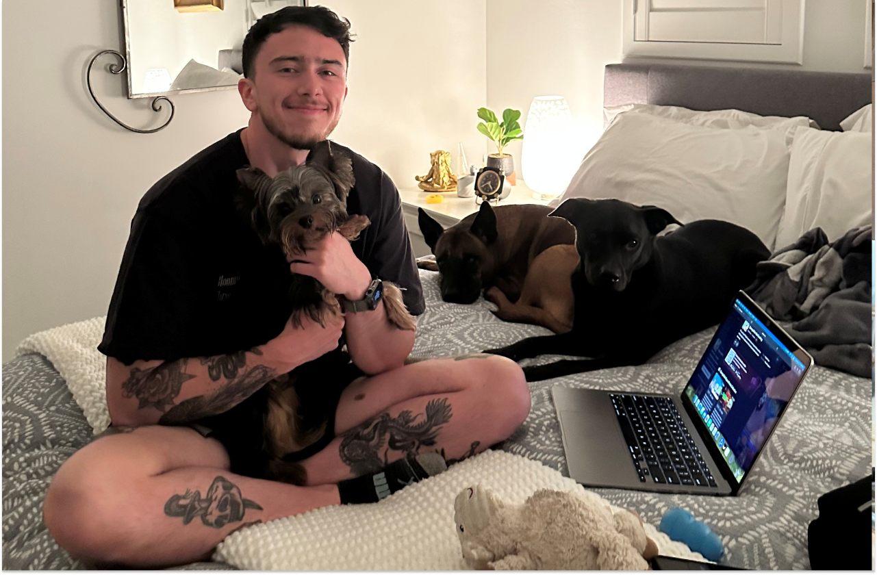 Hunter sat on his bed with 3 dogs and a laptop