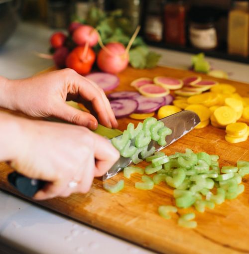 Hand chopping vegetable on wooden cutting board during corporate wellness workshop