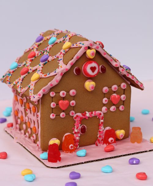 Valentine's Day-themed gingerbread house ingredients, featuring colorful candies, prepared during a festive corporate team building workshop.