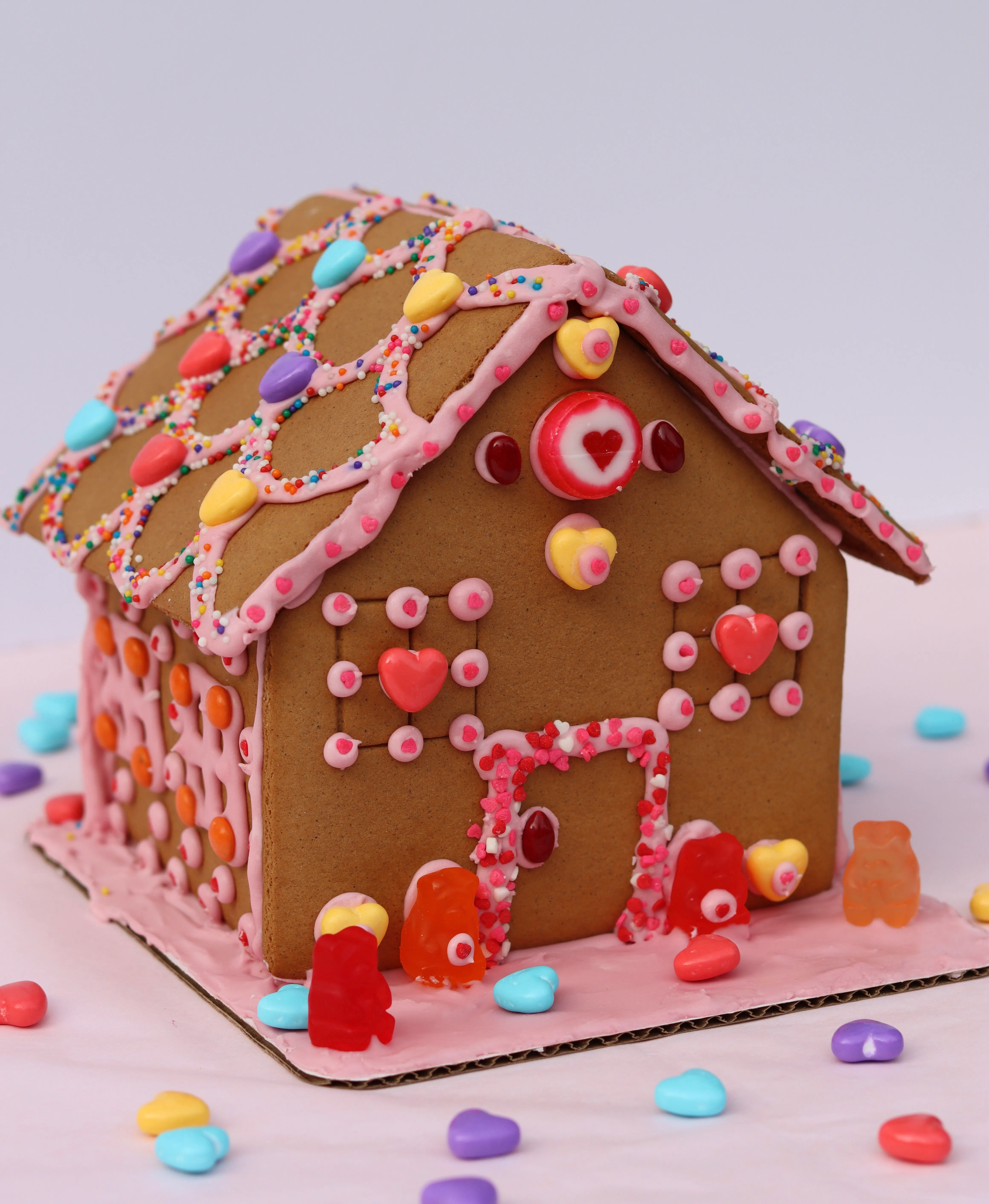 Valentine's Day-themed gingerbread house ingredients, featuring colorful candies, prepared during a festive corporate team building workshop.