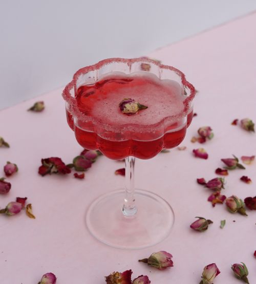 Valentine's Day truffles plated on a white dish with dried rose buds, against a pink background, as made in both virtual and in-person workshops.