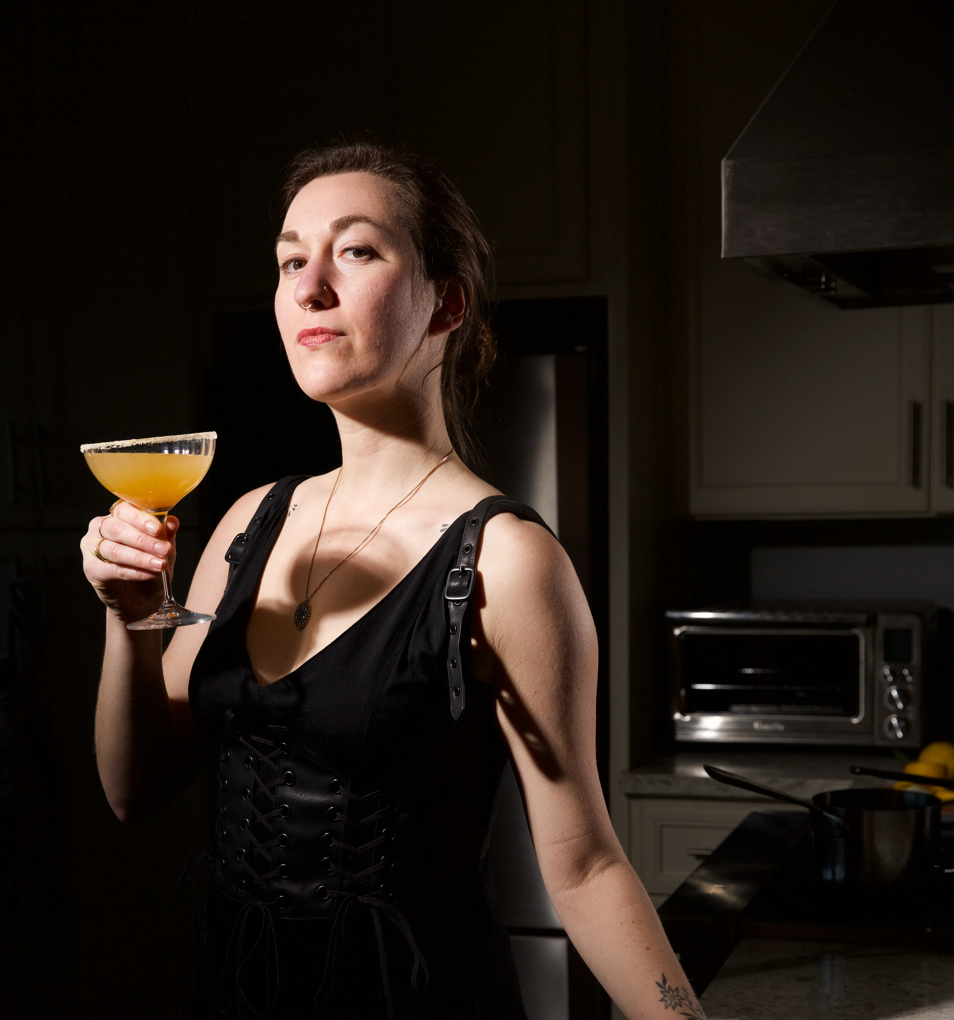 Halloween-themed mocktail on checkered background, garnished with an orange slice and plastic spider decorations made during a seasonal corporate event