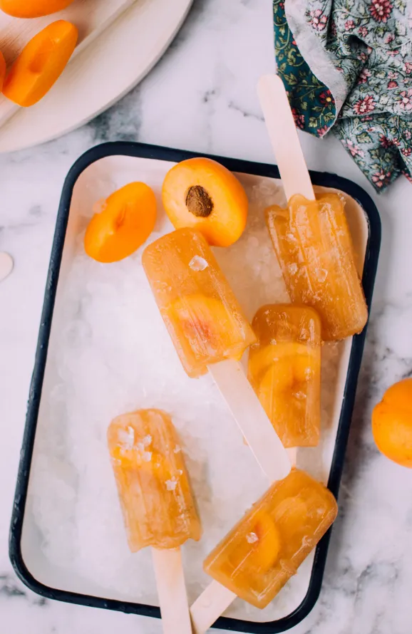 Peach popsicles on a granite kitchen counter top.