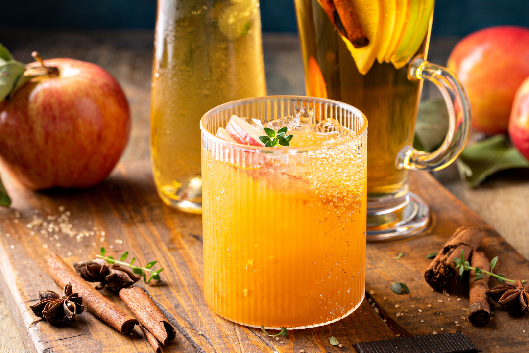 Apple cider margarita mocktail with herbs on wooden table during virtual mixology class