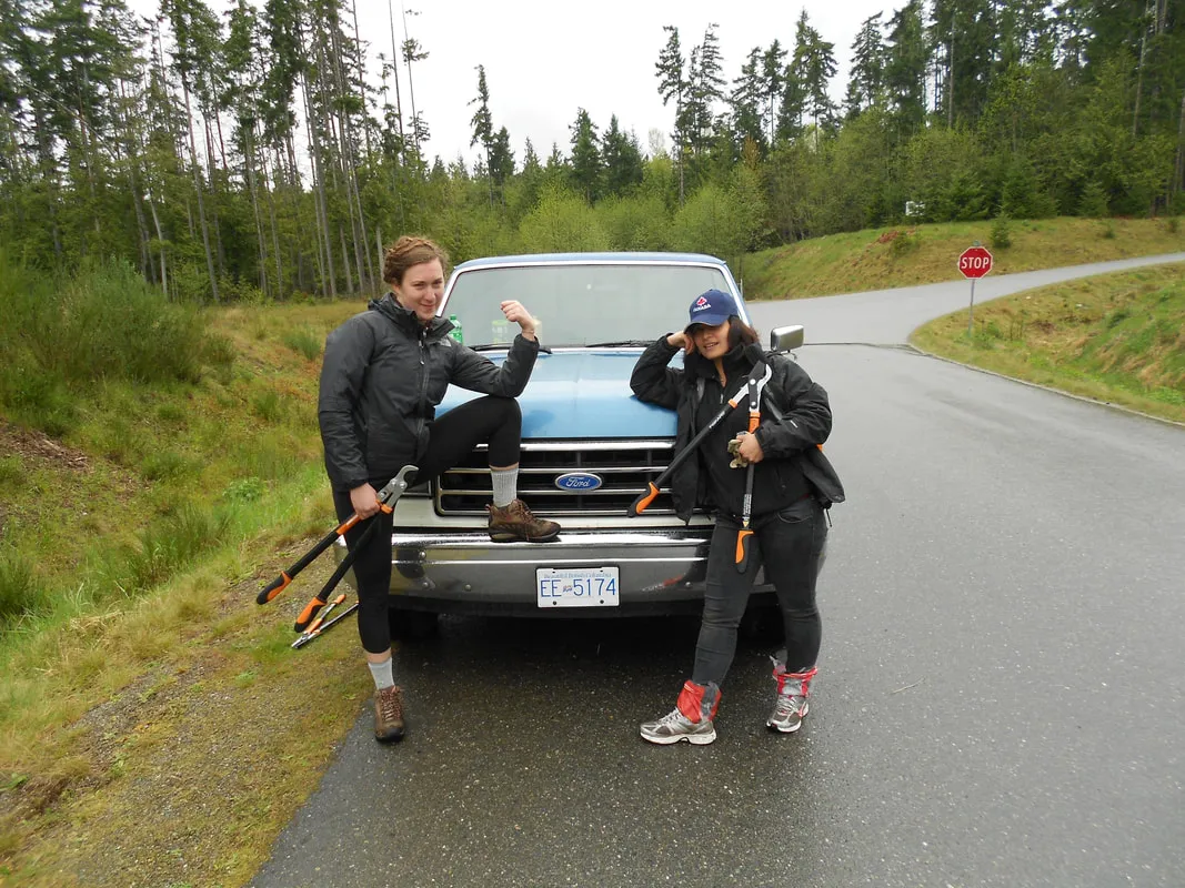 two women posing in front of truck with pruning sheers
