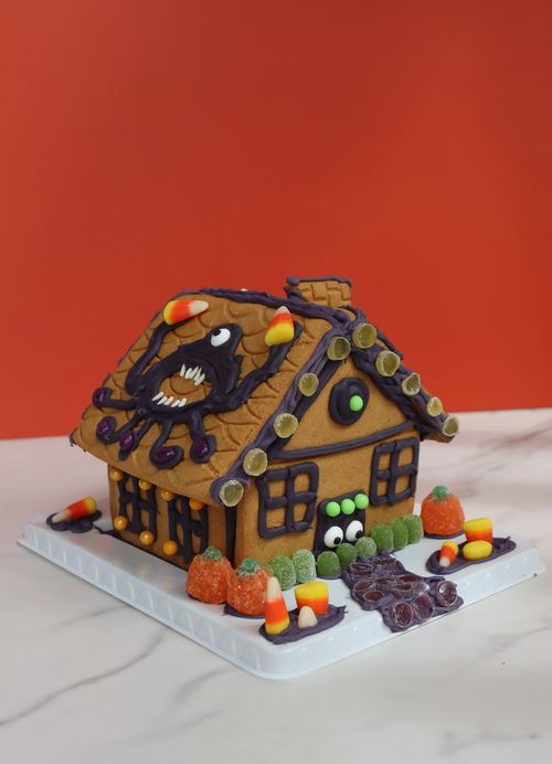 Halloween-themed gingerbread house cookie with candy decorations made for festive team-building activities
