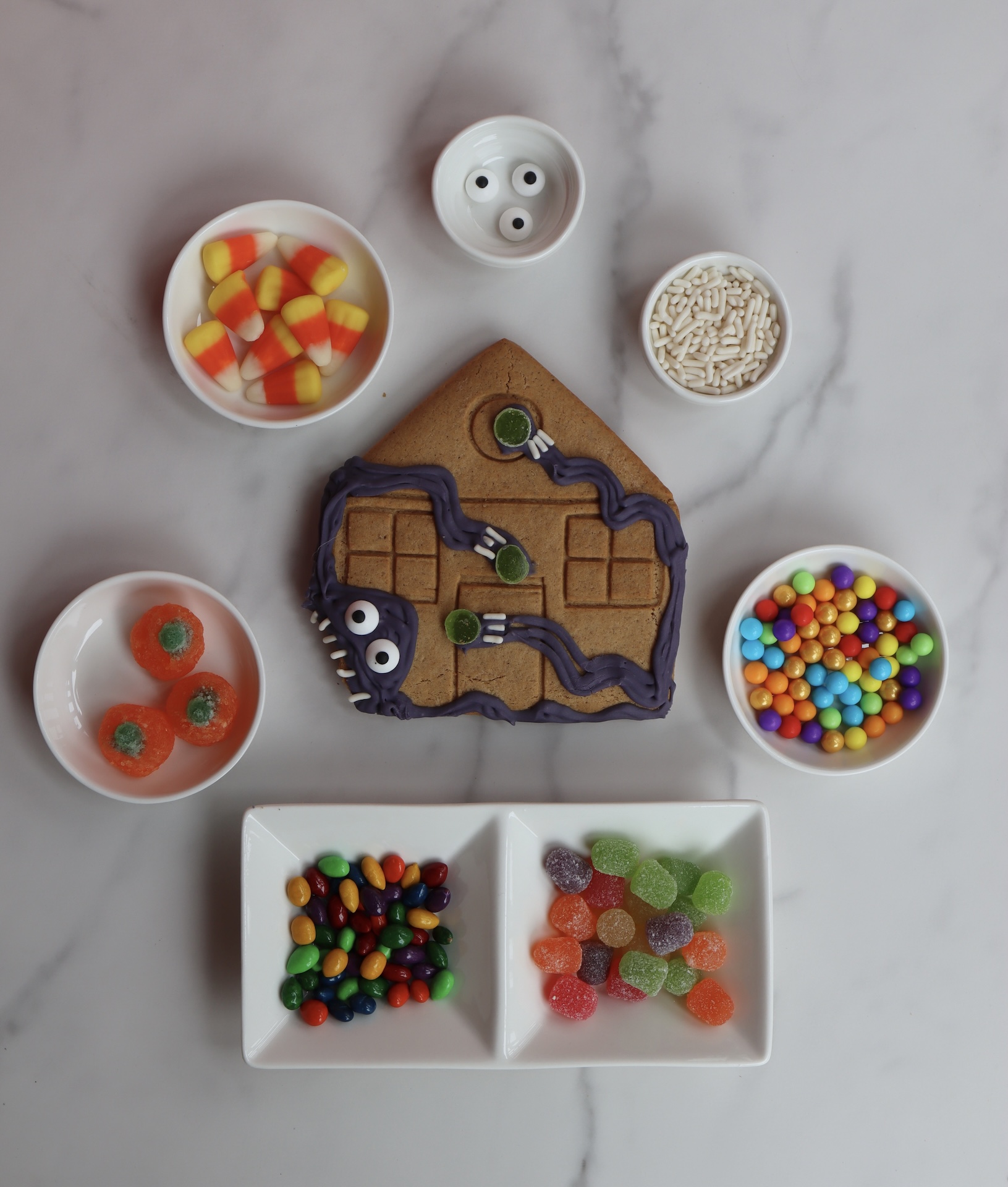 Halloween-themed gingerbread house cookie with candy decorations made for festive team-building activities