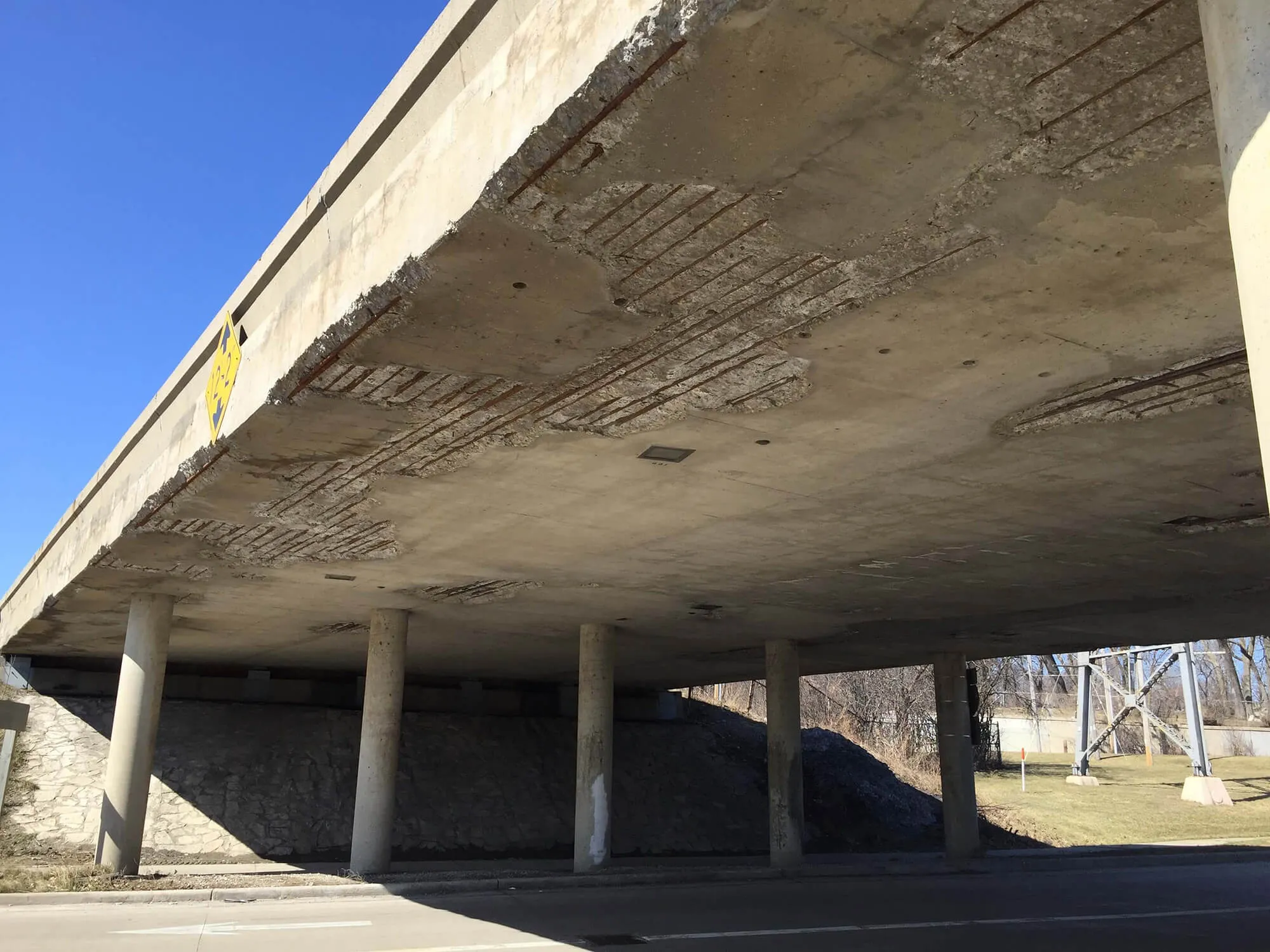 The underside of a bridge over I-94 with deteriorating concrete.