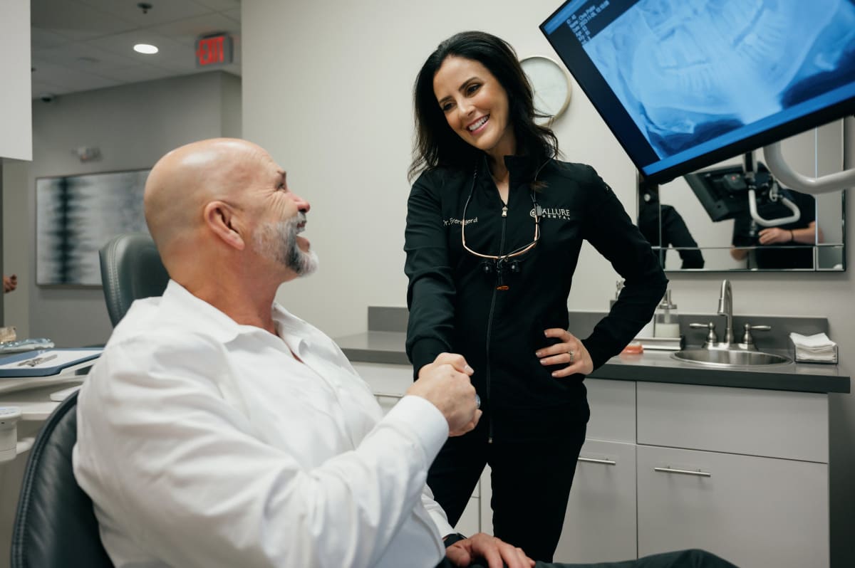 Female dentist consulting with male patient in modern dental office treatment room