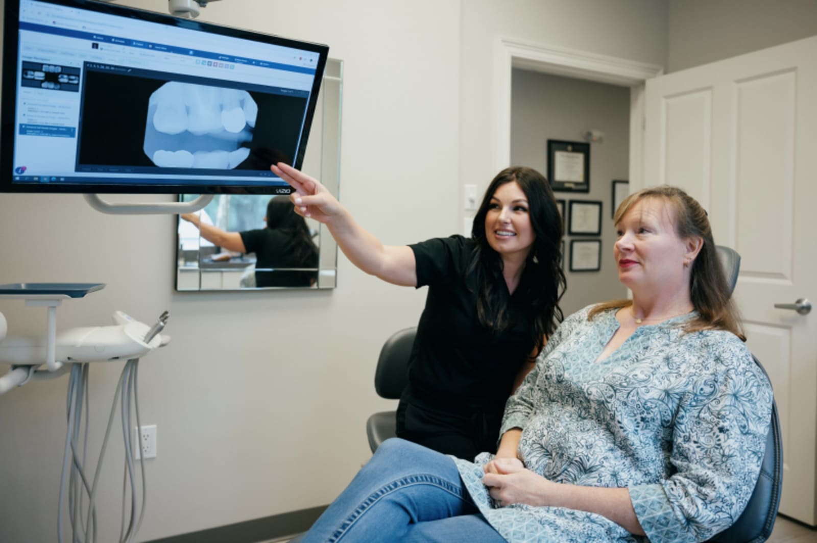 Dentist showing patient digital X-ray and smile design on treatment monitor