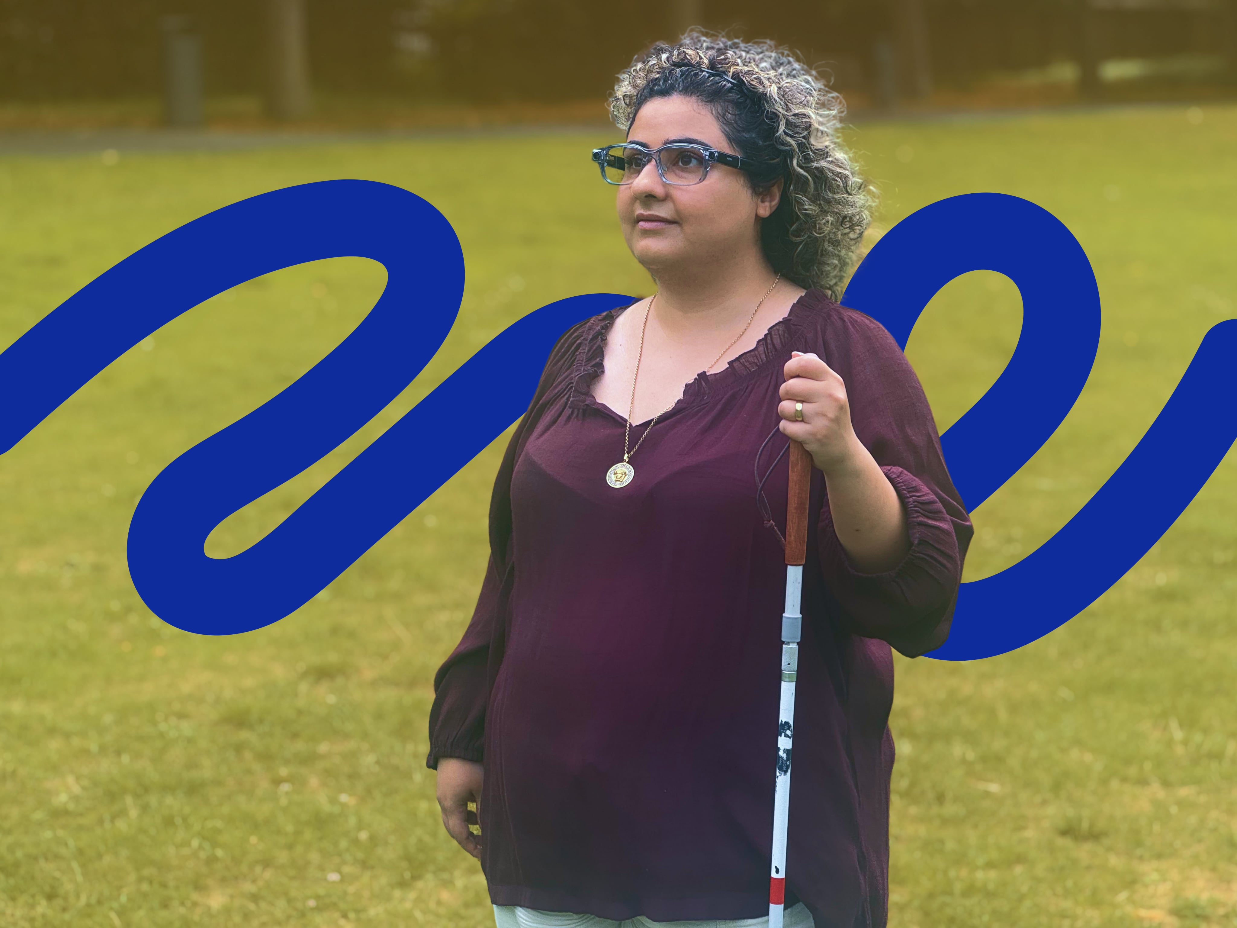 A woman with curly hair wearing the ally Solos Glasses, she's holding a white cane and standing on a grassy field. There is an ally artwork-style behind her.