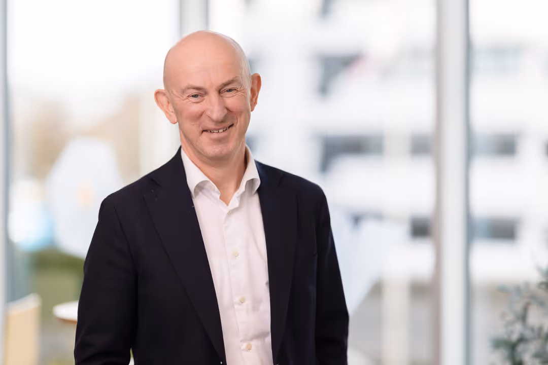 Bedriftsportrett Rogaland – seniorrådgiver i mørk blazer foran lyse kontorvinduer.