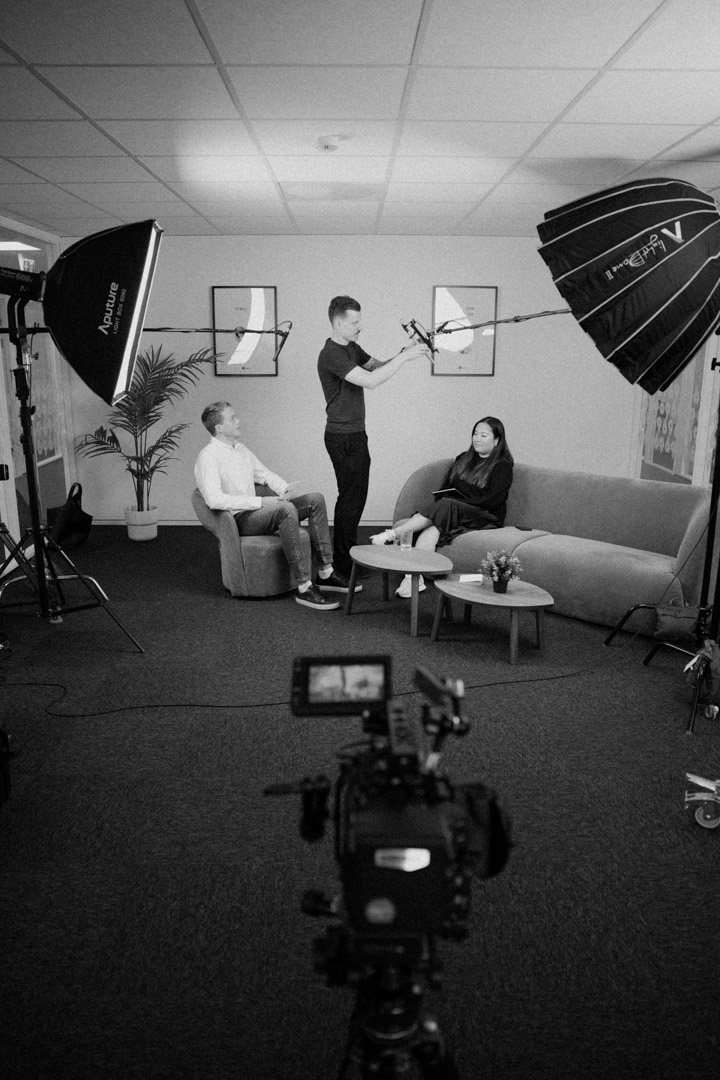 Bak kulissene i studio: to personer på sofa intervjues med lysrigg, boom-mikrofon og hovedkamera – stillsfoto & video Stavanger.