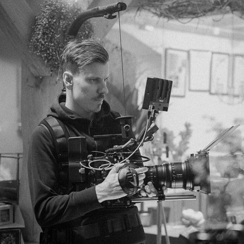 Filmskaper fra Flare i Stavanger med profesjonell kamerarigg under en innendørs videoproduksjon. Fokus på kvalitet og filmproduksjon bak kulissene.