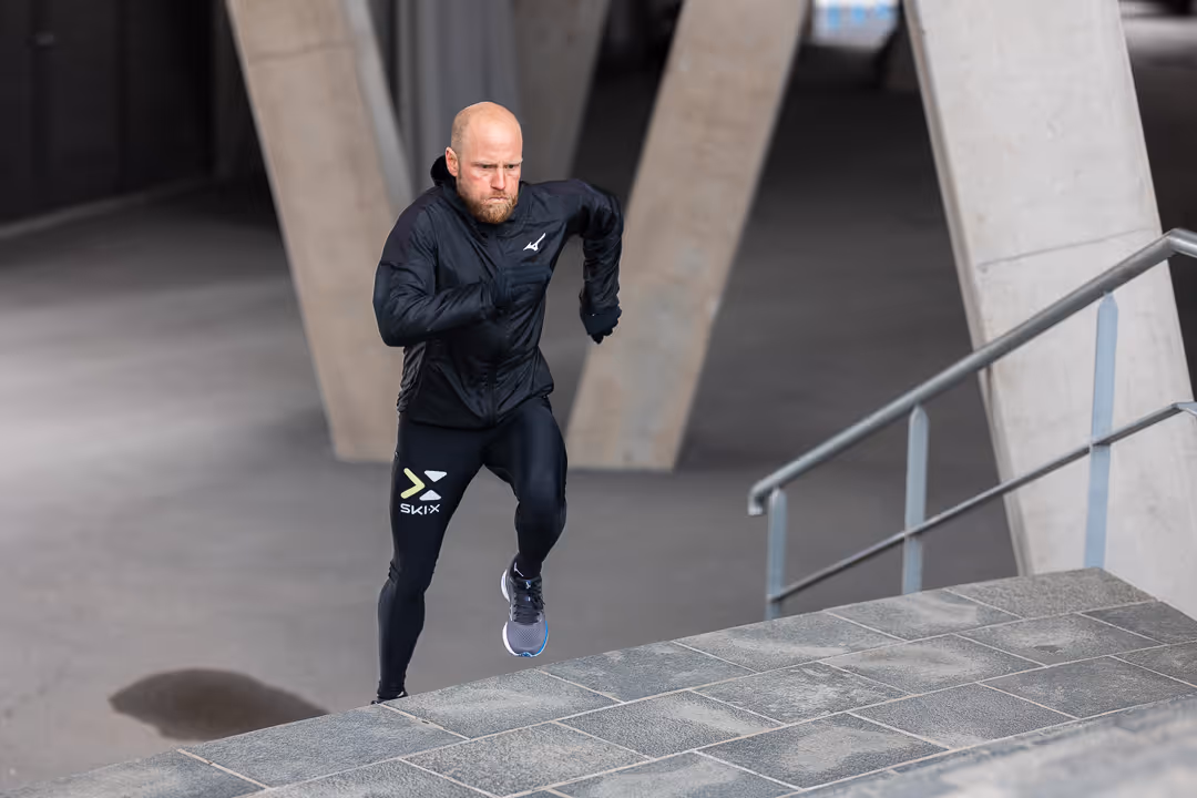 Løper i helsvart Mizuno-tøy spurter opp betongtrapp i byrom – sportsfotografering Oslo.