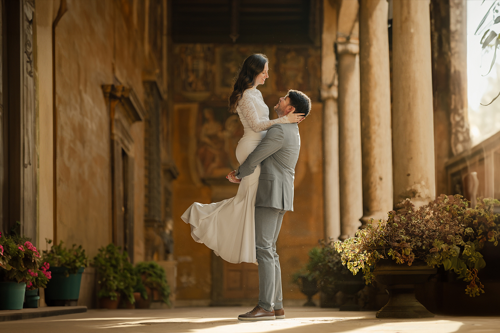 Couple photoshoot in a golden Roman courtyard—man lifting partner, captured by a local Rome photographer