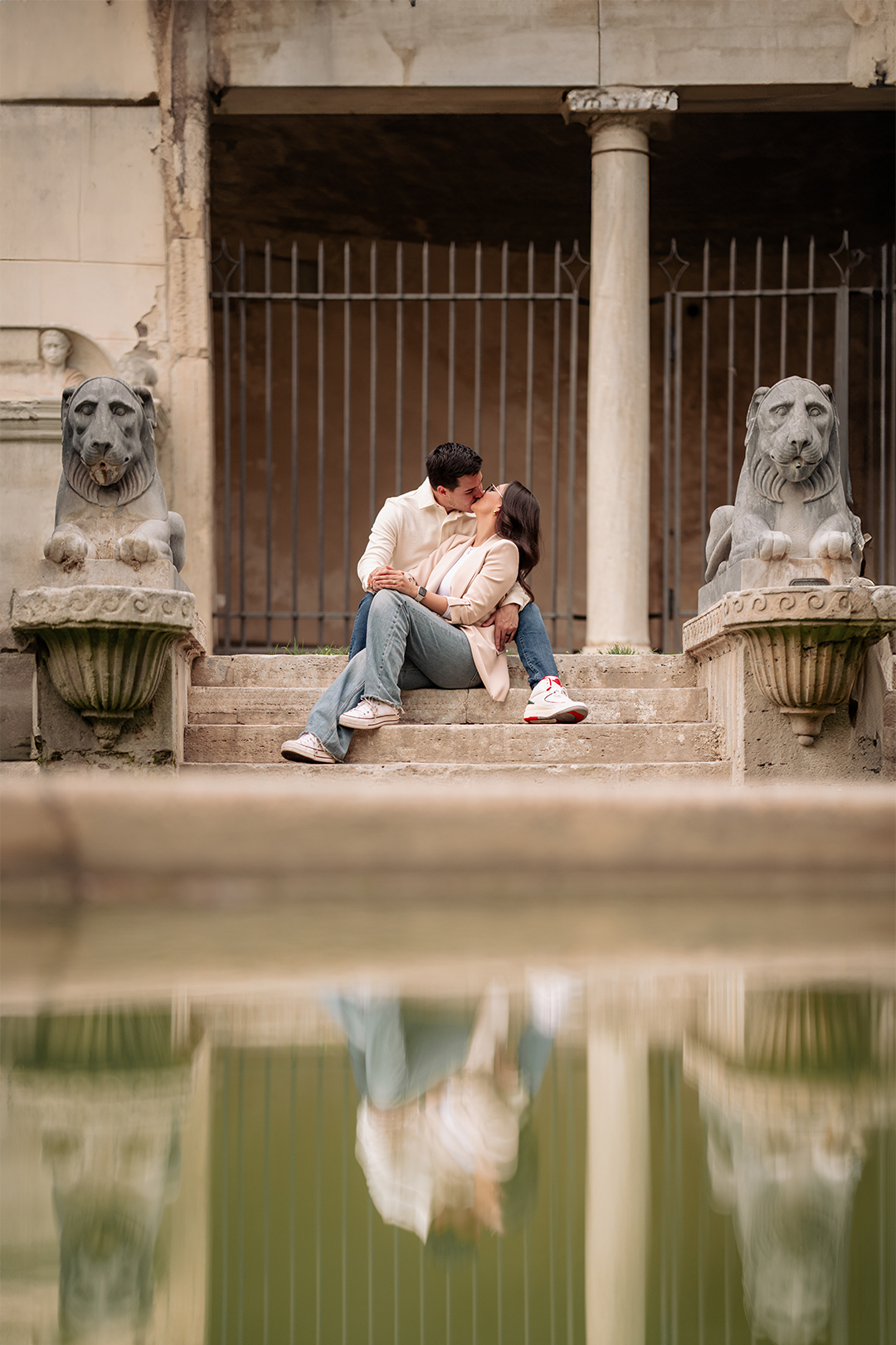 Romantic couple kissing on stone steps between lion statues during a photoshoot at Villa Borghese in RomeRomantic couple kissing on stone steps between lion statues during a photoshoot at Villa Borghese in Rome