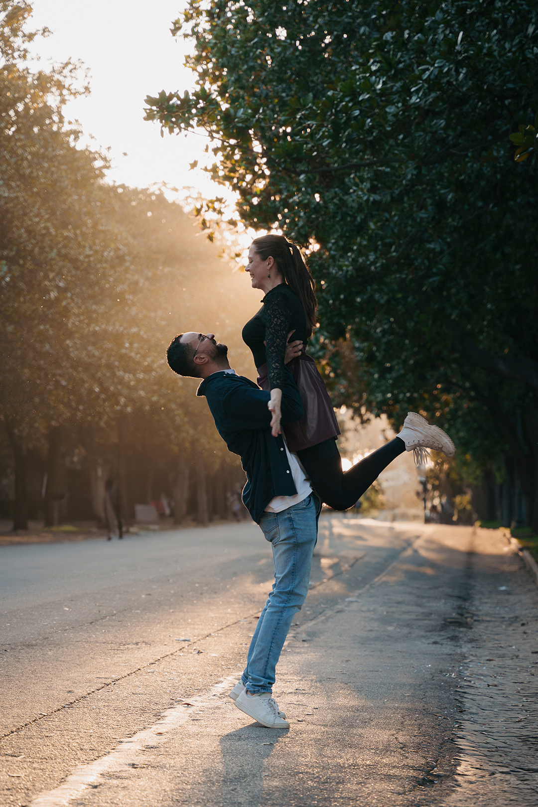 Couple photoshoot at Villa Borghese during golden hour in Rome, romantic lift pose under the trees