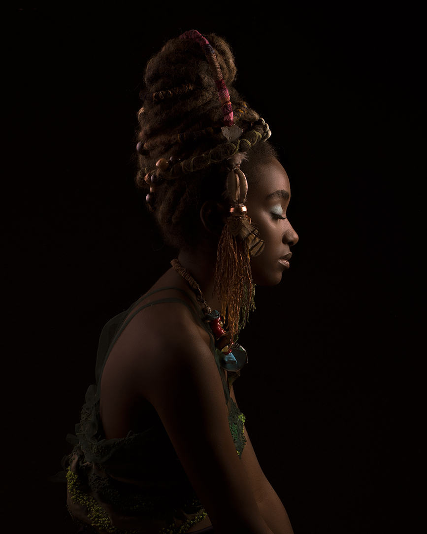 Low-key fashion portrait of a model with a sculptural hairstyle against a dark background