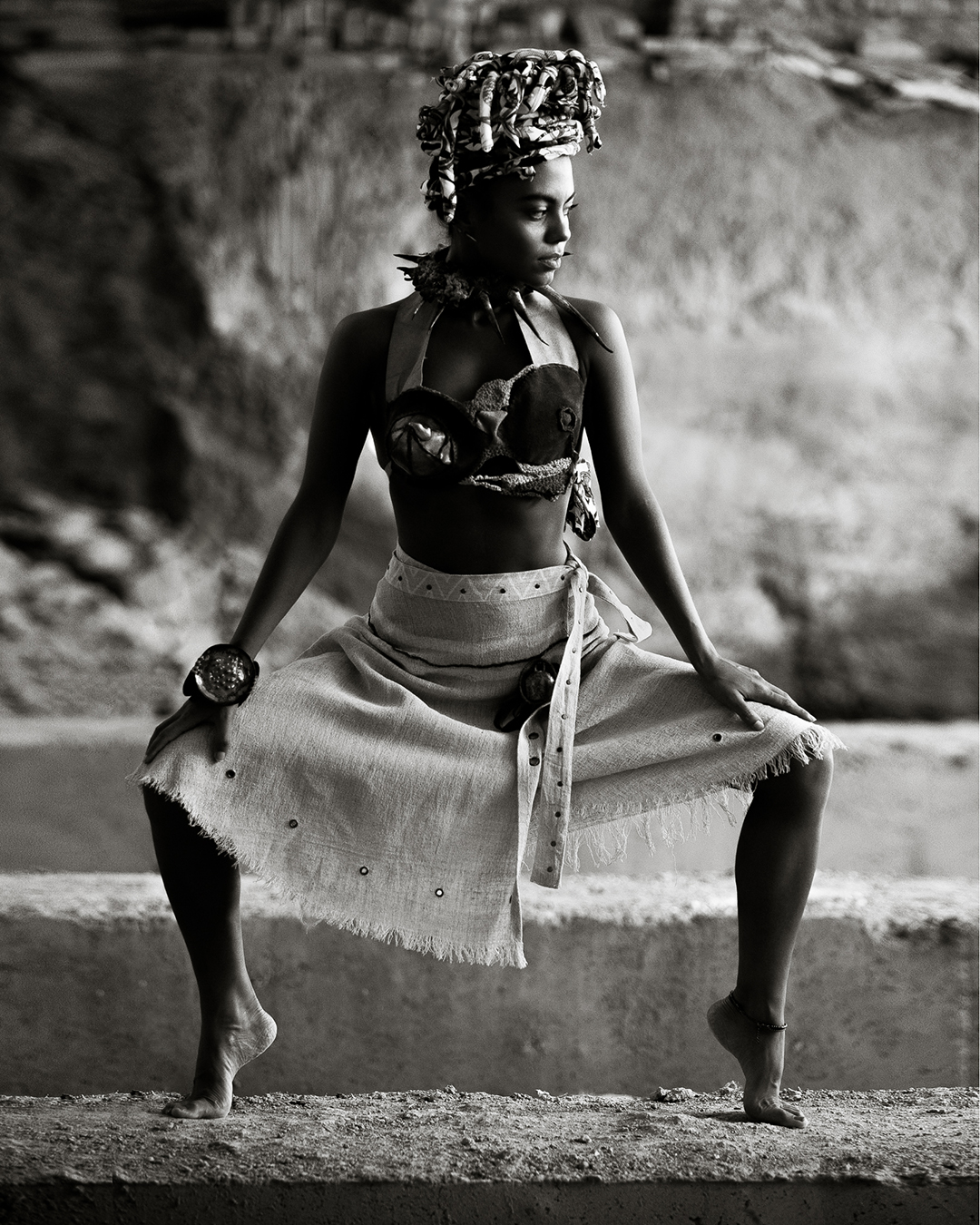 Black and white fashion portrait of a model crouching in a bold pose wearing jewelry