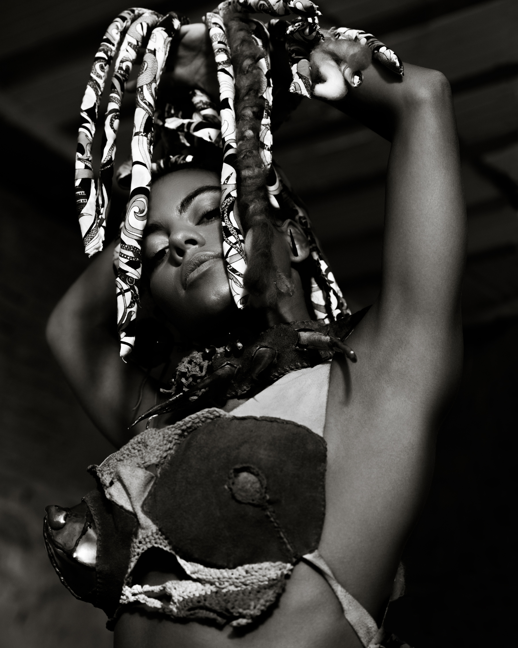 Dramatic low-key fashion portrait of a model in ornate beaded jewelry with one arm raised