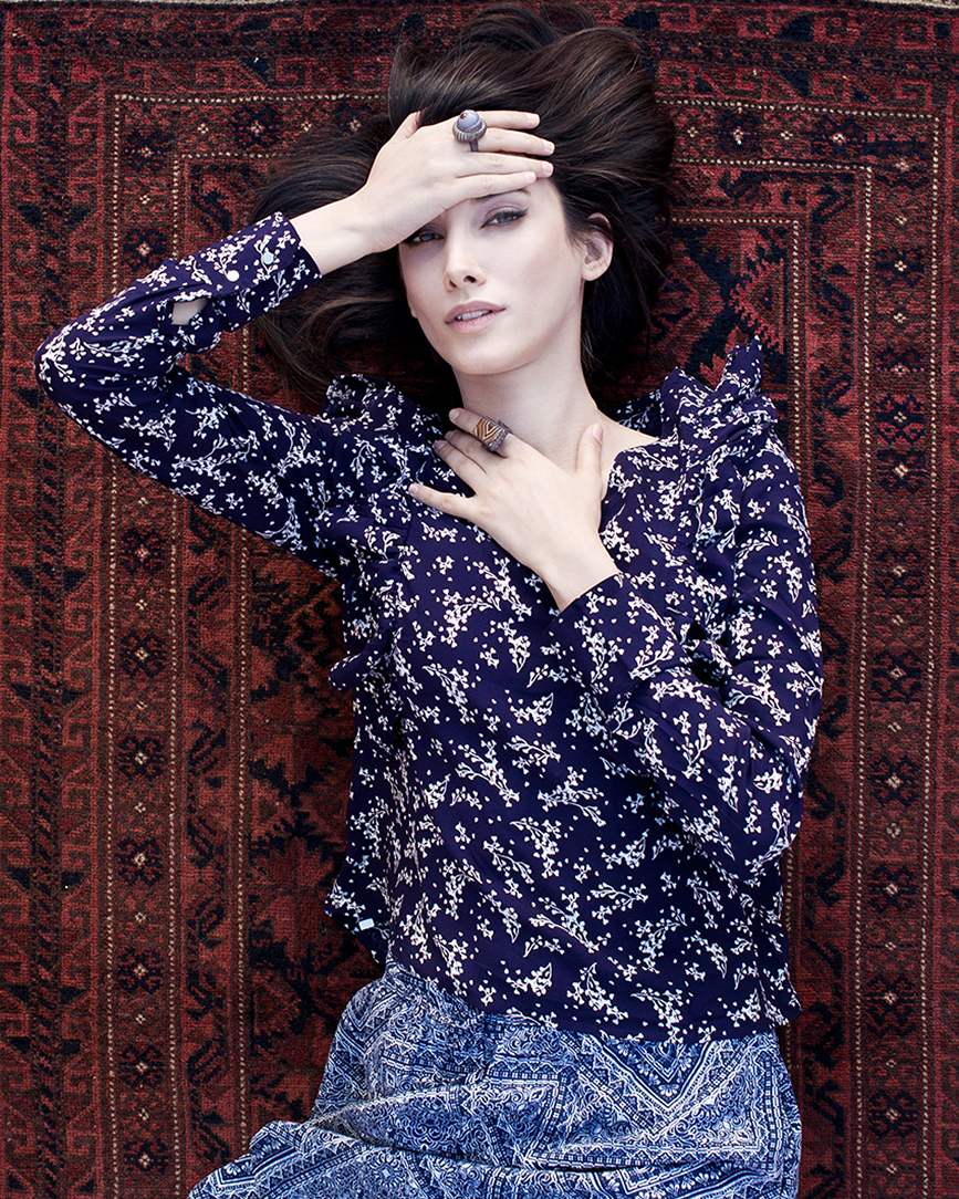 Fashion portrait of a model in a floral blouse and skirt seated on a patterned rug