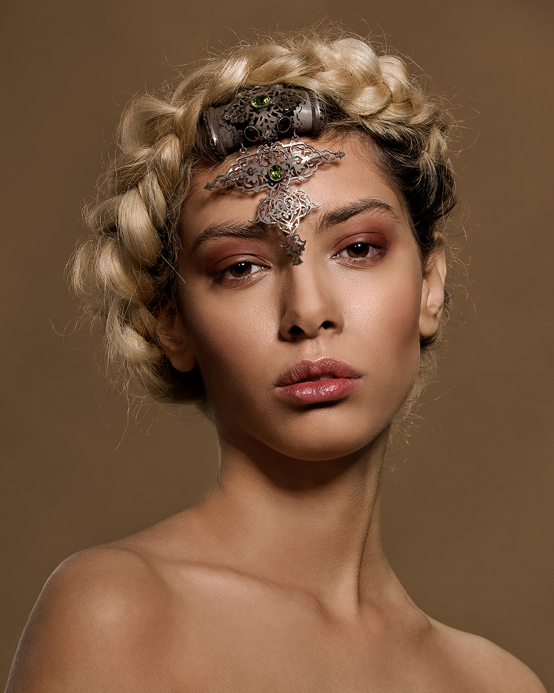 Fashion beauty portrait of a model with a braided updo and a jeweled headpiece across the forehead