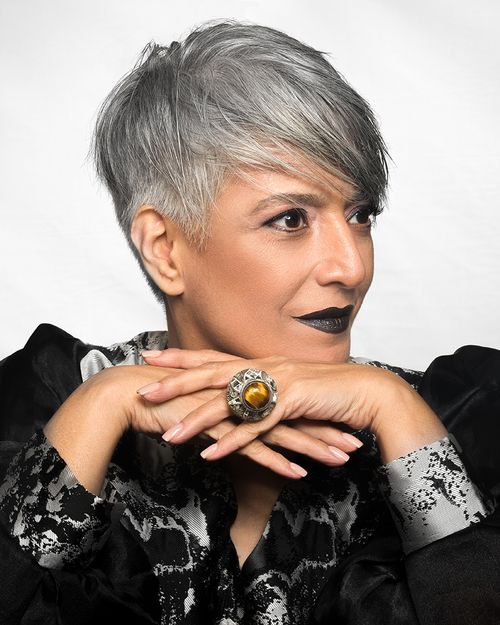 Fashion portrait of a model with short silver hair in an embellished dark jacket and rings