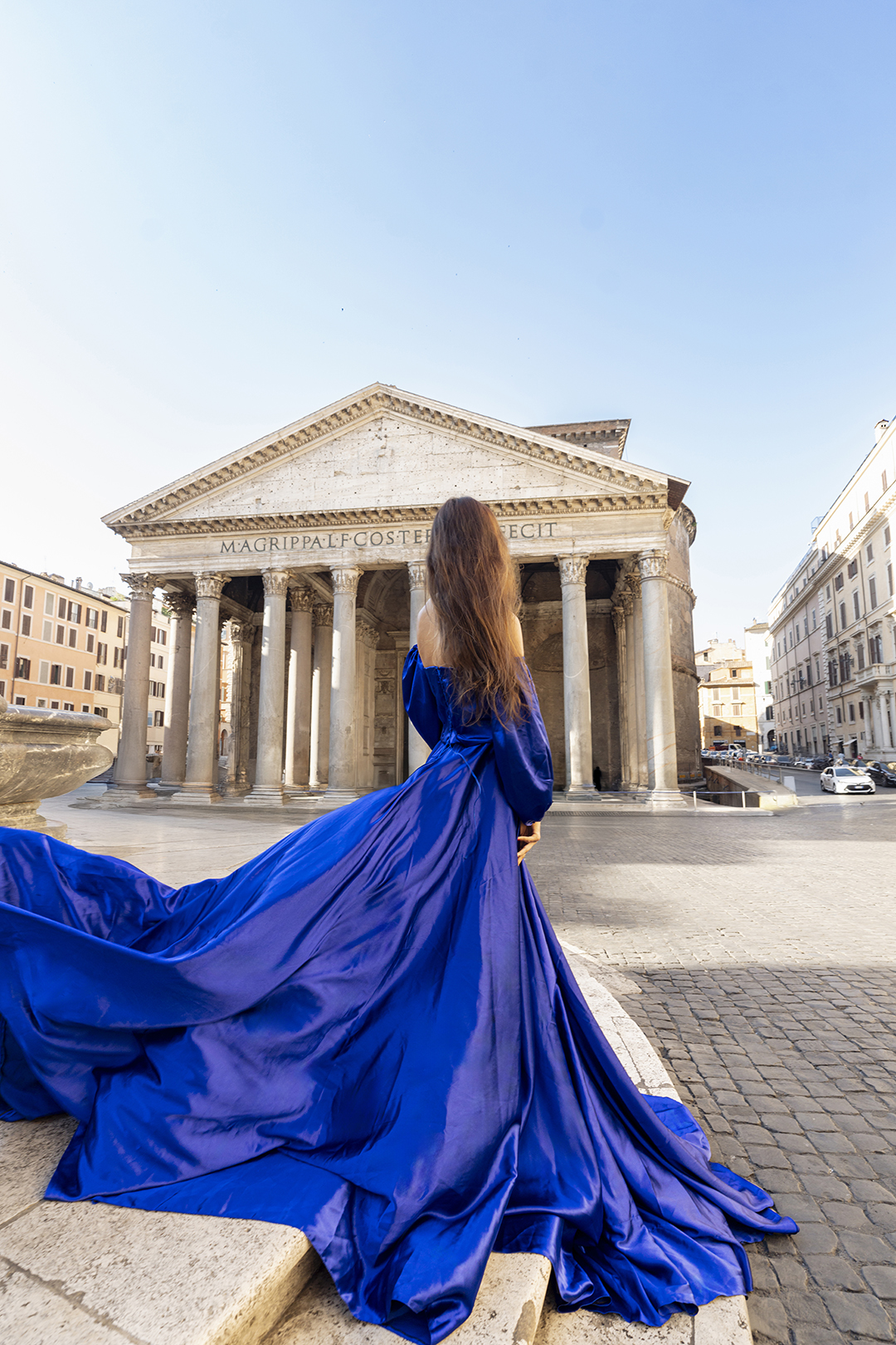 Royal-blue flying dress with long train facing the Pantheon portico in Rome, Piazza della Rotonda.