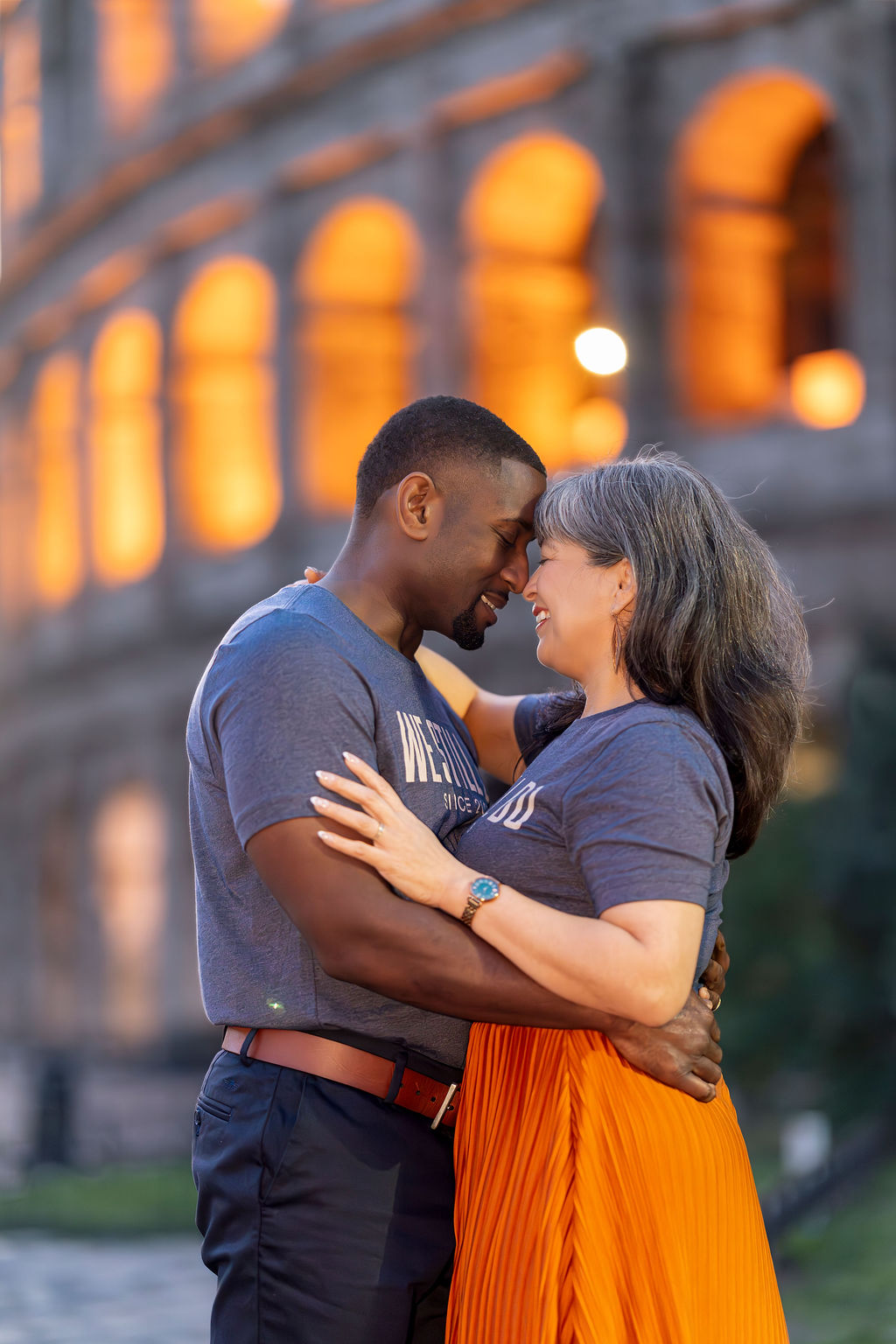 Close-up portrait of couple embracing under Colosseum arches glowing with warm light during Blue Hour — Rome couple photoshoot by Eidos Photography.