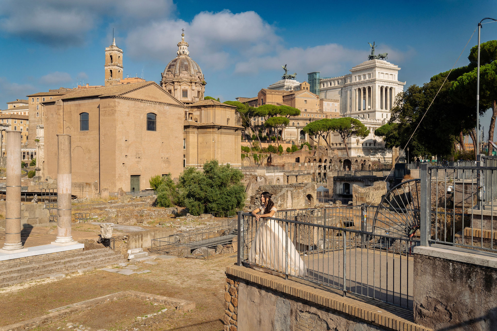 quinceañera in an ivory ball gown looking over the Roman Forum from a terrace on Via dei Fori Imperiali, with domes and the Altare della Patria in the background at first light in Rome