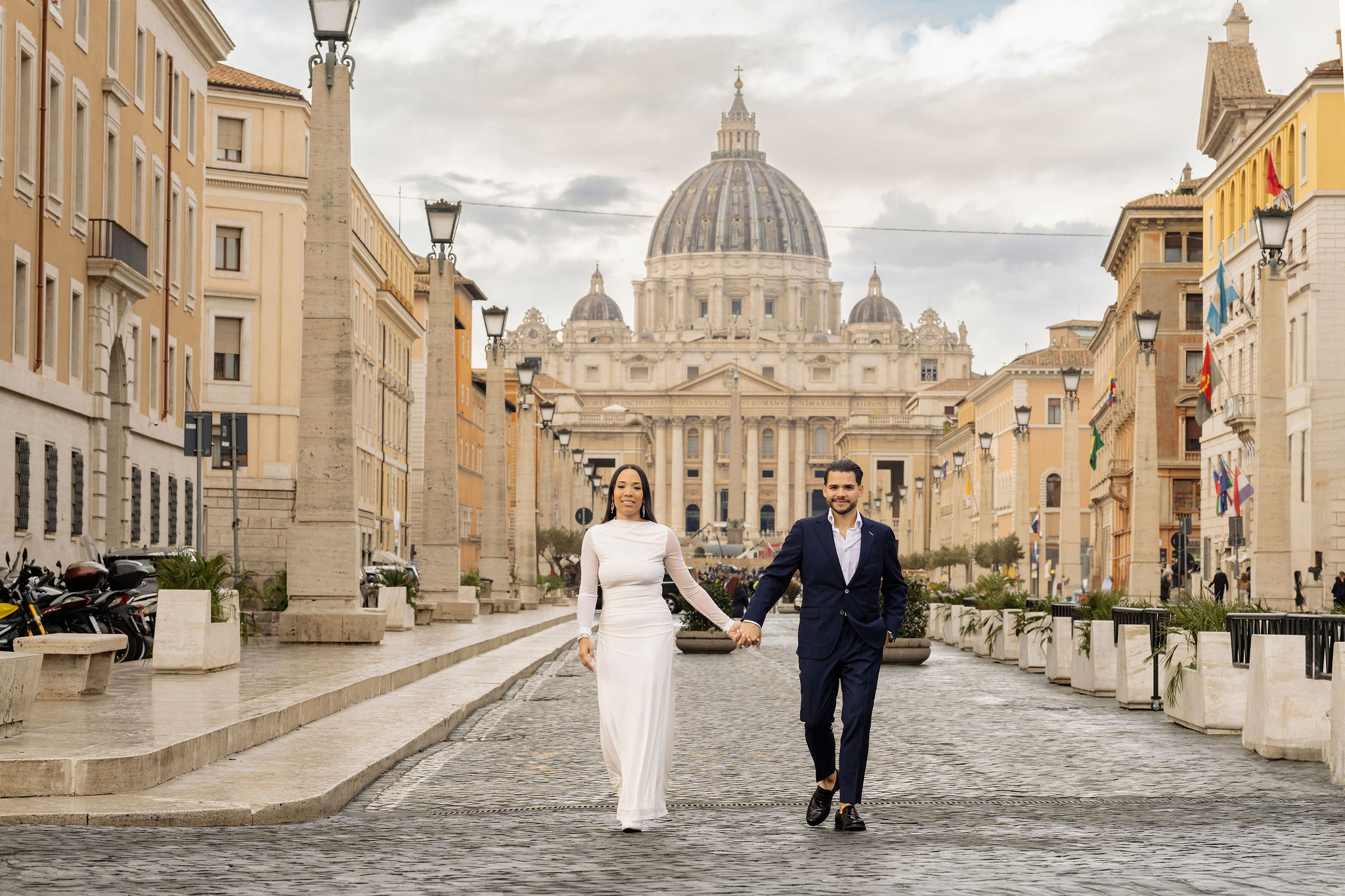 Couple walking hand in hand on Via della Conciliazione with St. Peter’s Basilica in the background during the Grand Tour Rome Photoshoot by Eidos Photography, Rome photographer.