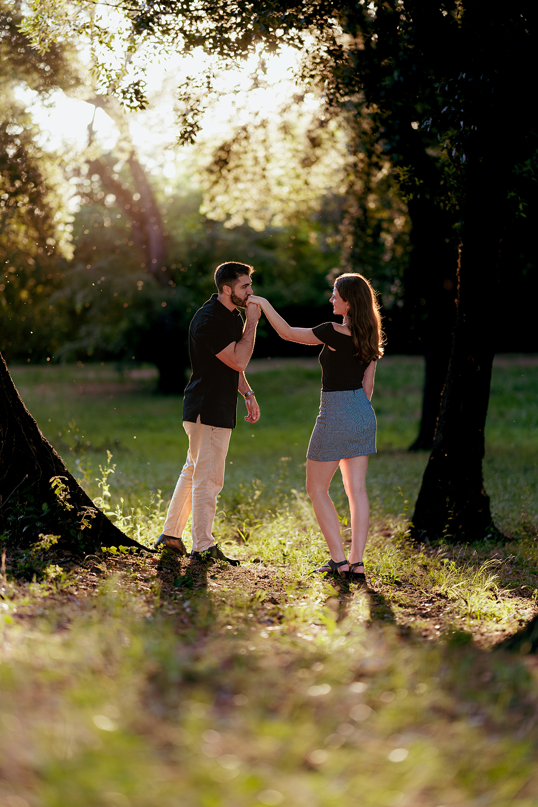 Romantic couple moment in Villa Doria Pamphili, Rome, man kissing her hand during a couple photoshoot with soft backlight and bokeh by Eidos Photography, Rome photographer.