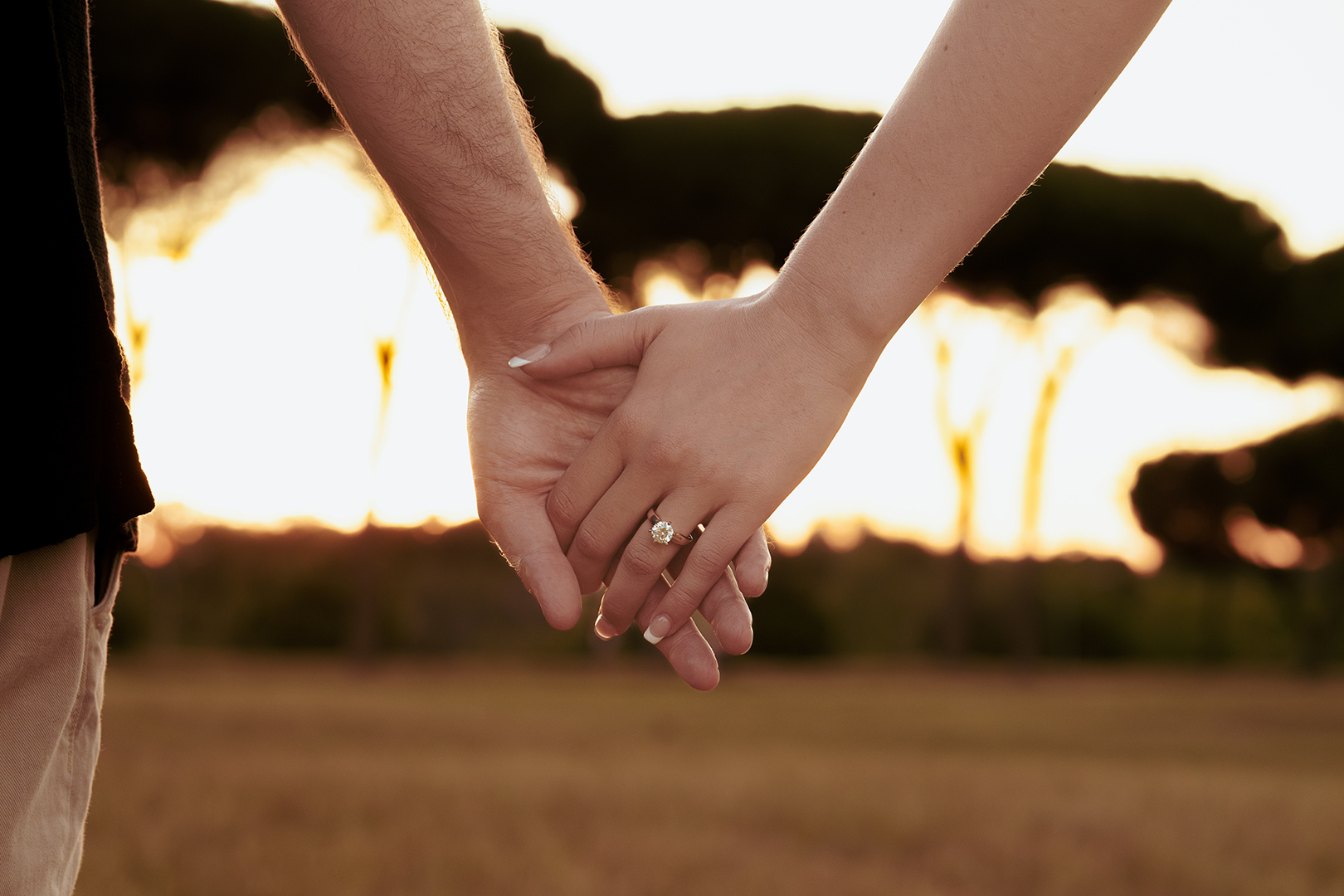 Close up of couple holding hands with engagement ring visible at golden hour in Villa Doria Pamphili, Rome, proposal photoshoot by Eidos Photography, Rome photographer.