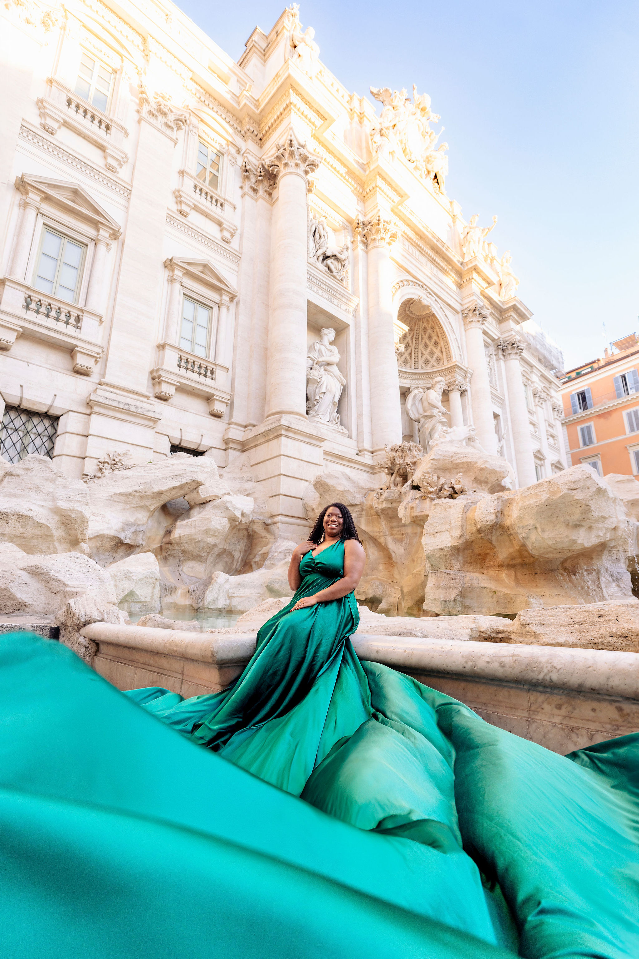 Dramatic final portrait of woman in flowing green flying dress at Trevi Fountain in Rome, private flying dress photoshoot by Eidos Photography Rome photographer.