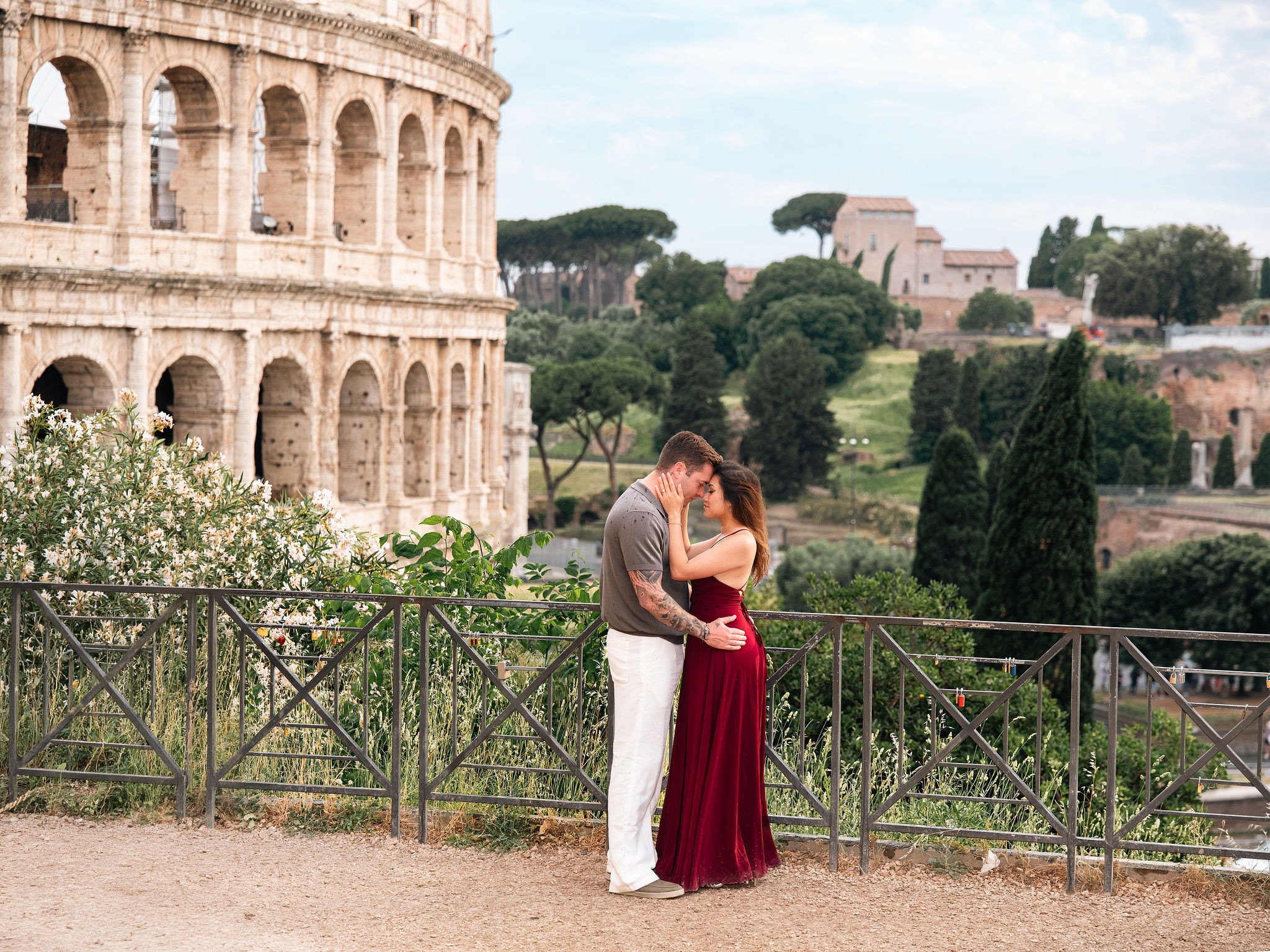 Couple embracing at Giardinetto del Monte Oppio during a secret proposal photoshoot in Rome with a romantic Colosseum view in the background.