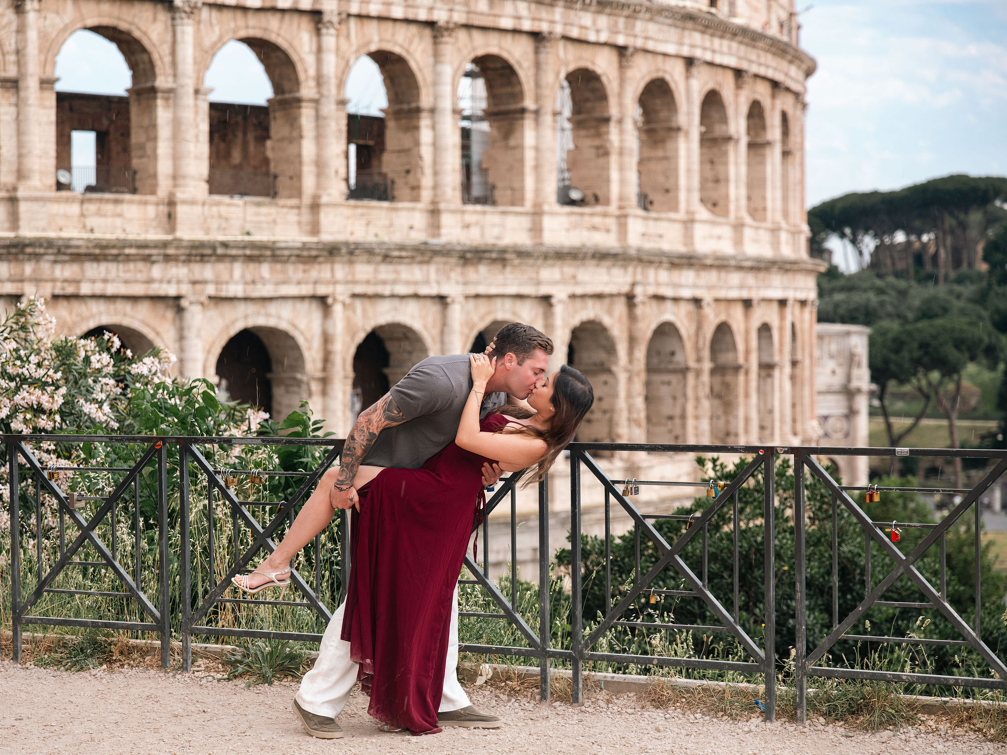Couple kissing during a romantic secret proposal photoshoot at Giardinetto del Monte Oppio with the Colosseum in the background in Rome.