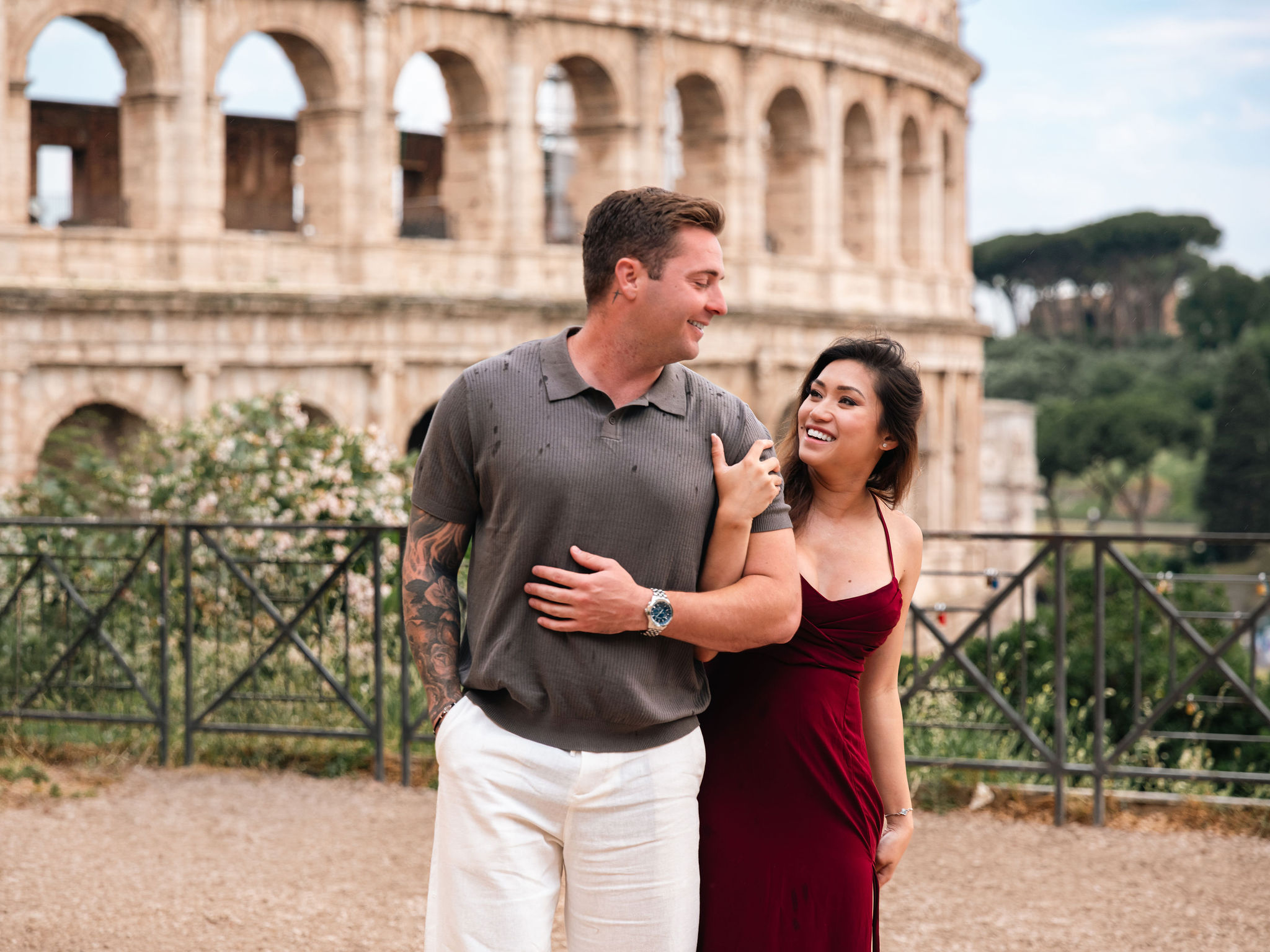Couple laughing during a romantic proposal photoshoot at Giardinetto del Monte Oppio with the Colosseum view in Rome.