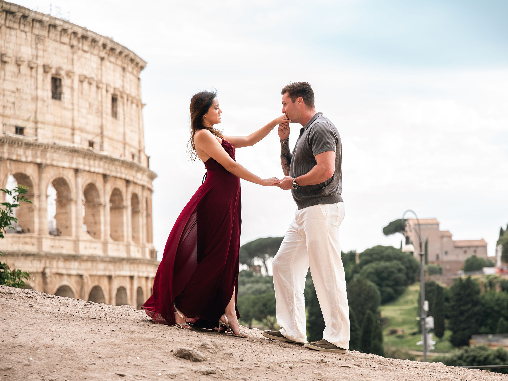 Couple holding hands during a romantic secret proposal photoshoot at Giardinetto del Monte Oppio with the Colosseum view in Rome.