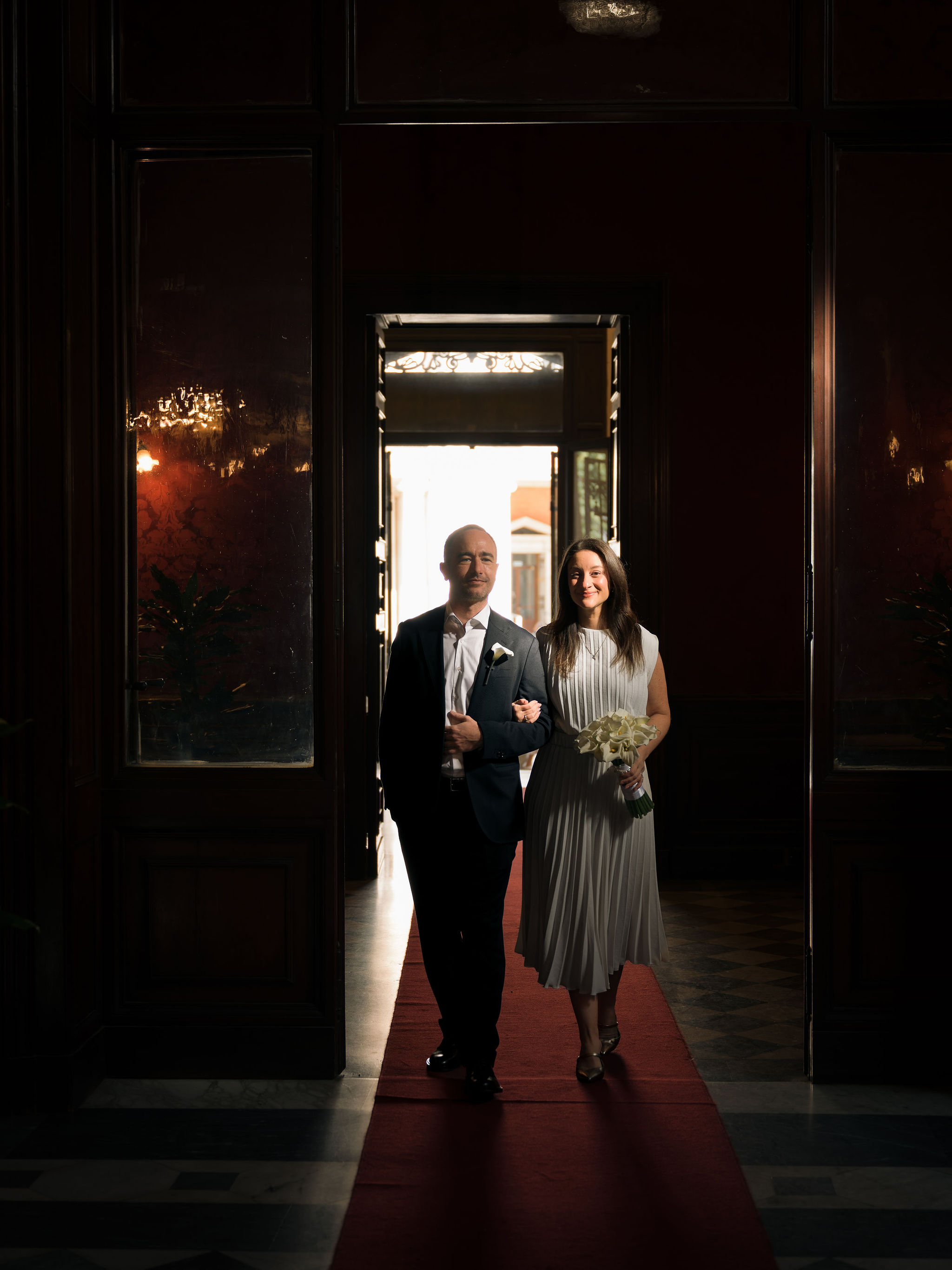 Couple walking arm in arm into the Sala Rossa at the Campidoglio in Rome for their civil wedding ceremony.