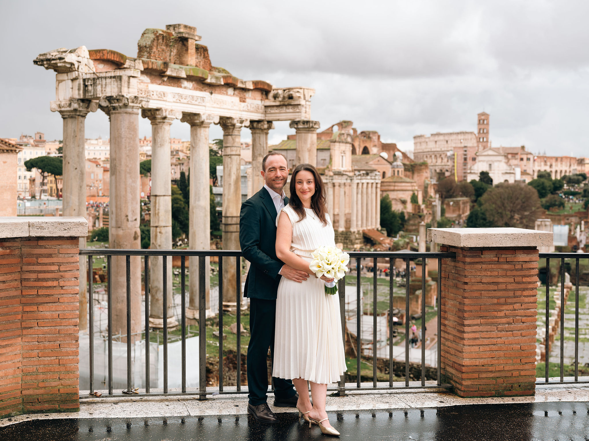 Newly married couple posing with a bouquet on the Capitoline Hill terrace overlooking the Roman Forum after their civil wedding in Rome.