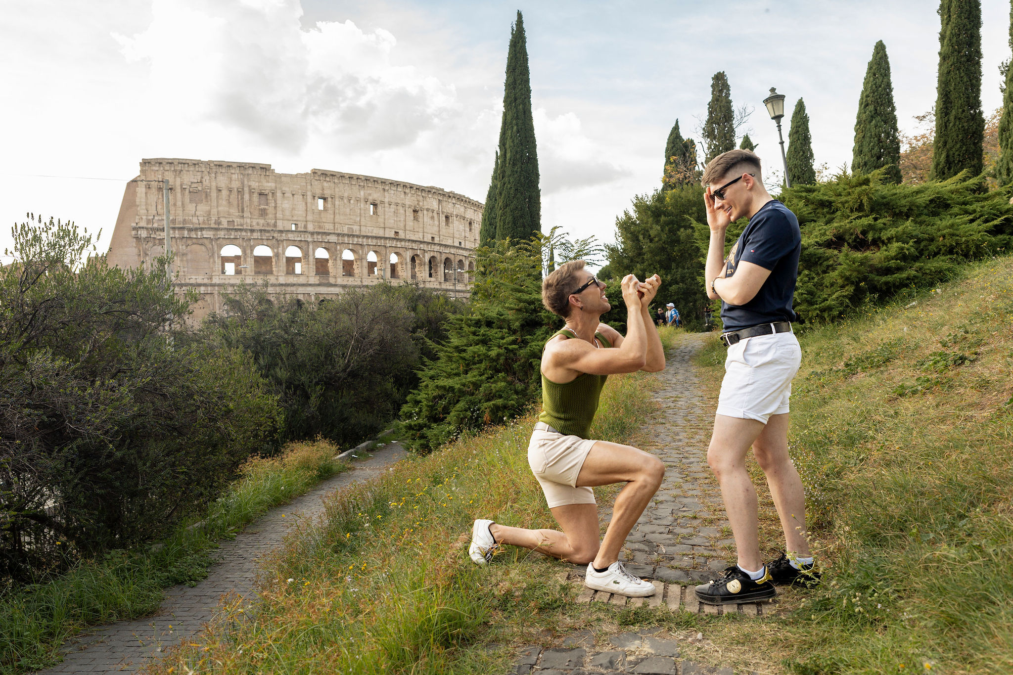 Same-sex proposal near the Colosseum in Rome, with one man kneeling as his emotional partner reacts to the surprise.