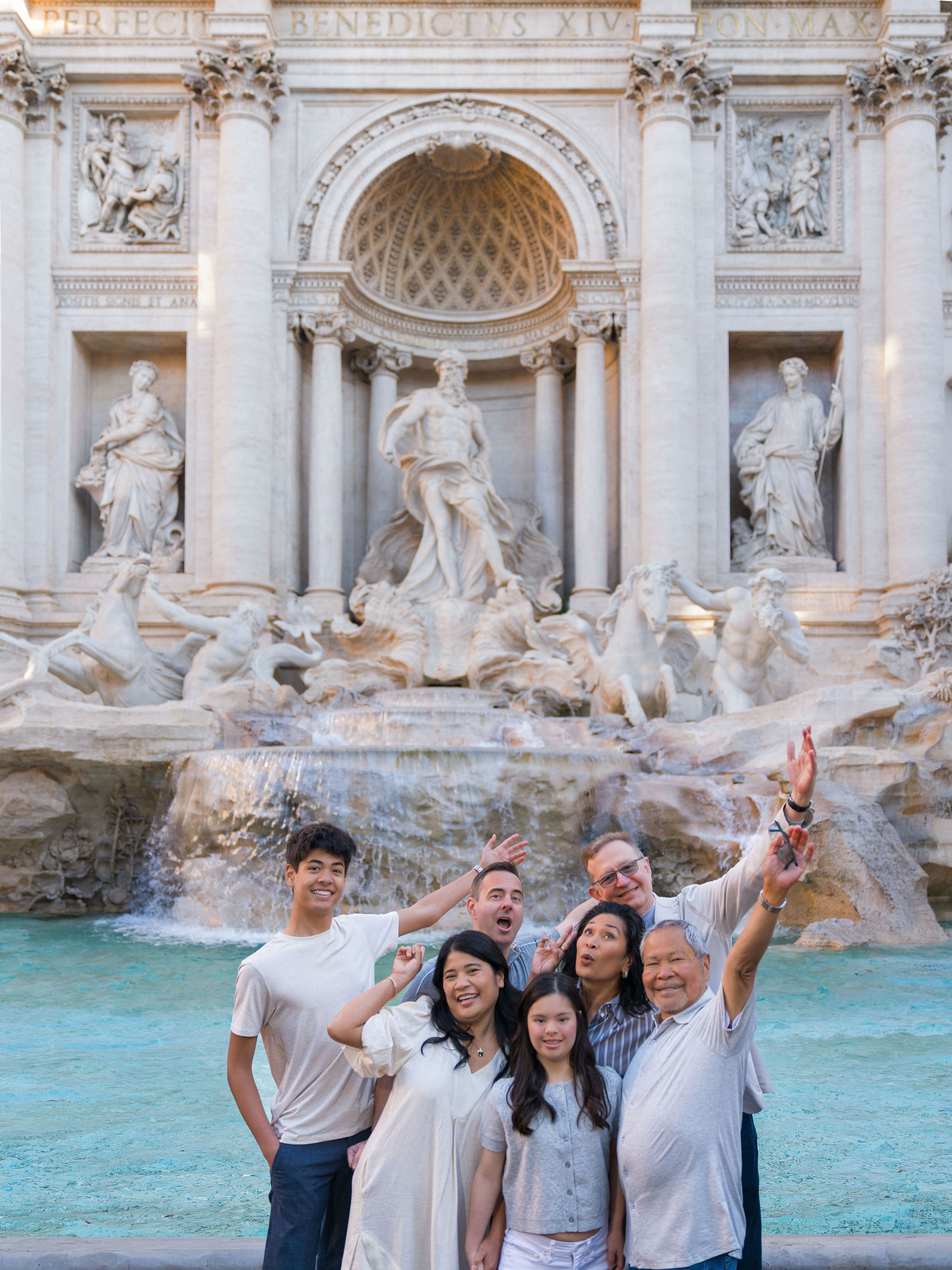 Multi-generational family enjoying a joyful moment together at the Trevi Fountain in Rome during a family vacation.