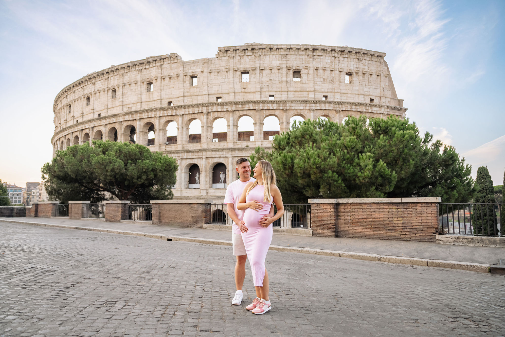     Expectant couple posing together during a babymoon photoshoot at the Colosseum in Rome.