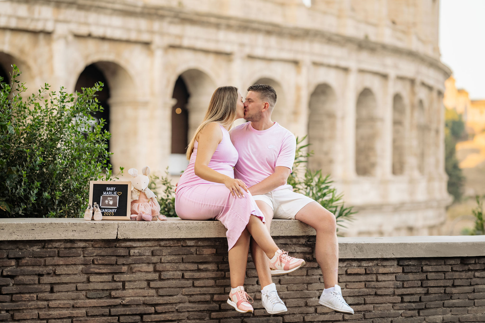     Smiling pregnant couple sharing an affectionate moment near the Colosseum.