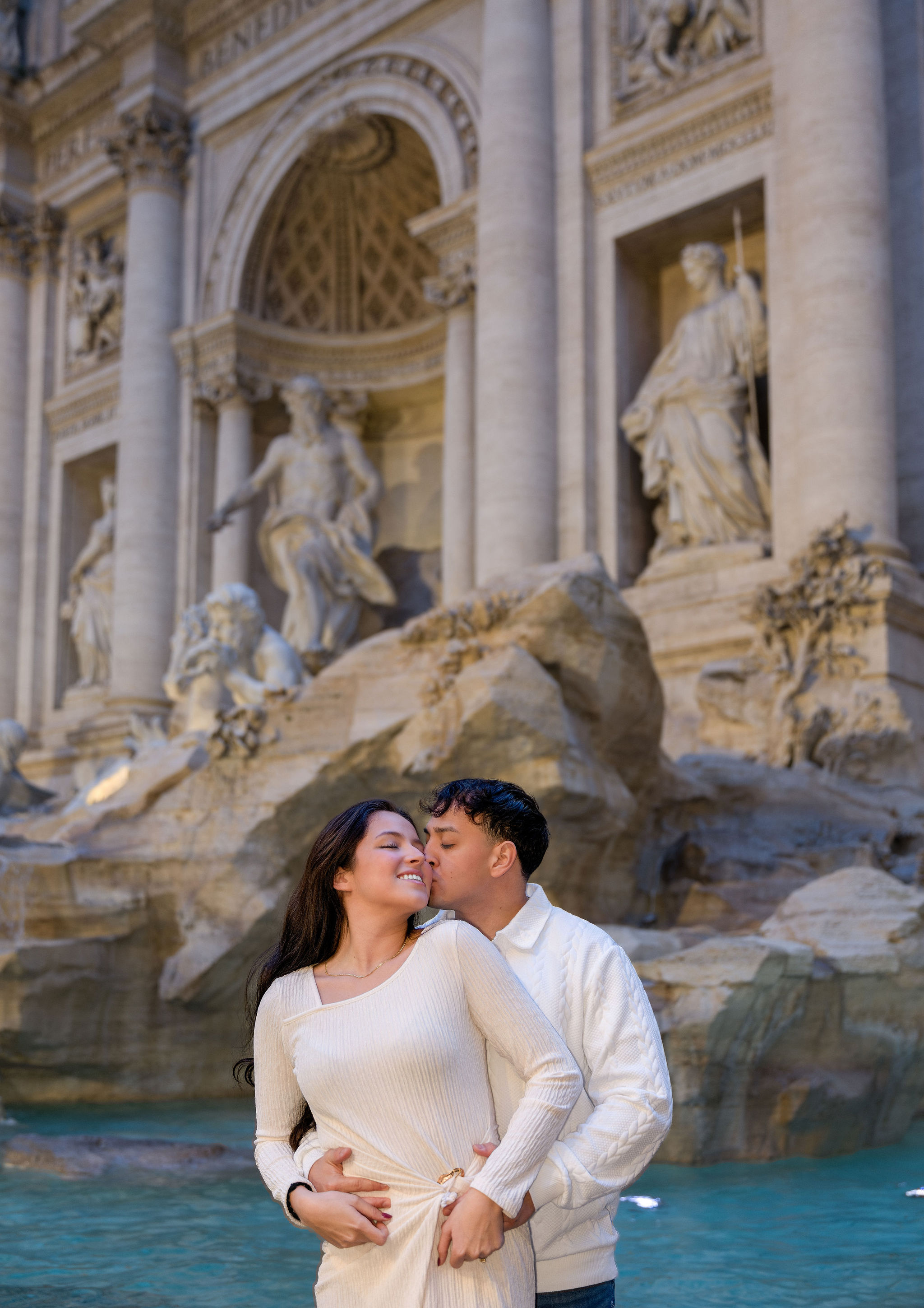 Couple embracing in front of the Trevi Fountain during a Rome photoshoot.