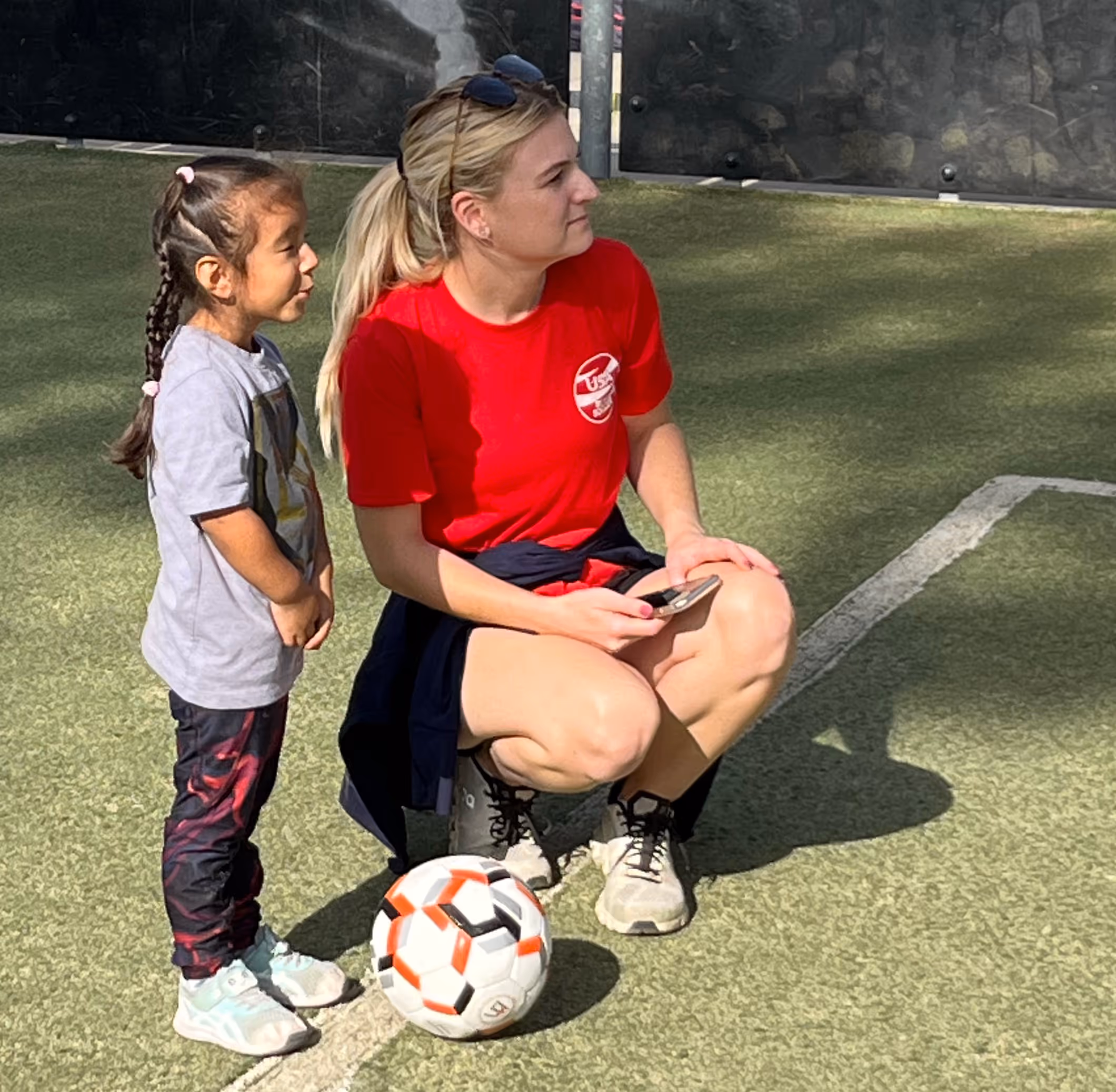 a young girl with an adult watching blind soccer game being played
