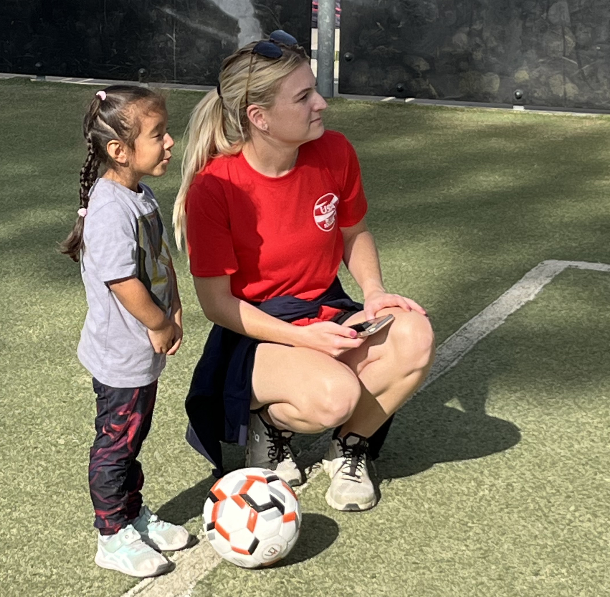 a young girl with an adult watching blind soccer game being played